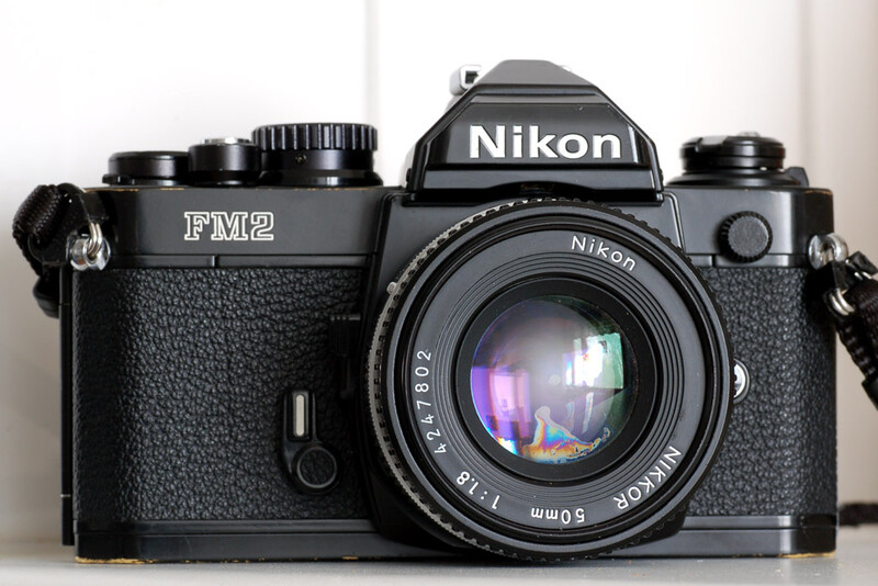 Nikon FM2 film camera with 50mm lens mounted, displayed against white background.