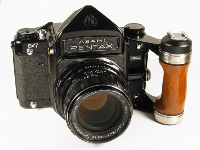 Asahi Pentax 67 film camera with standard lens and accessory viewfinder mounted on wooden grip.