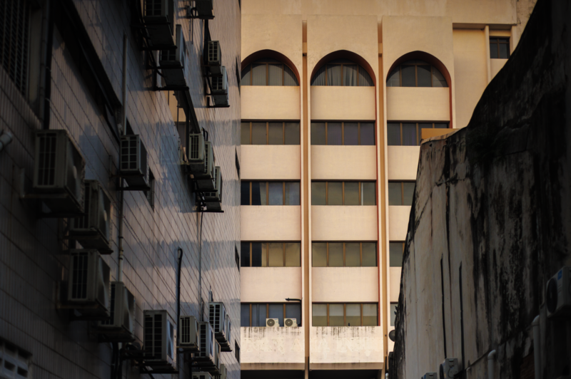 Modernist building with distinctive arched windows framed between narrow historic structures.