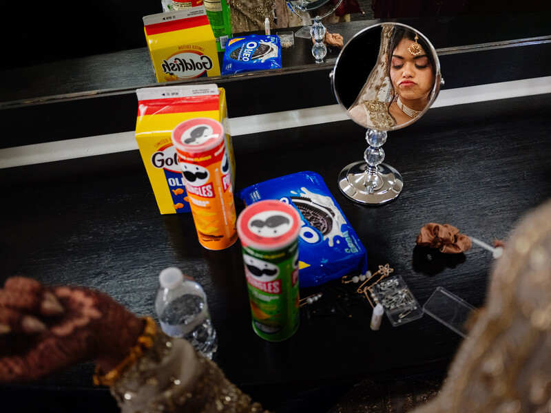 Tabletop still life with cosmetic products, decorative items, and a vanity mirror reflecting a person's face.