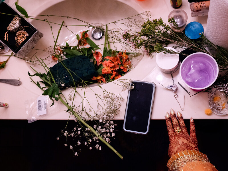 Flat lay composition of flowers, candles, smartphone, and decorative items arranged on pink and black surfaces.