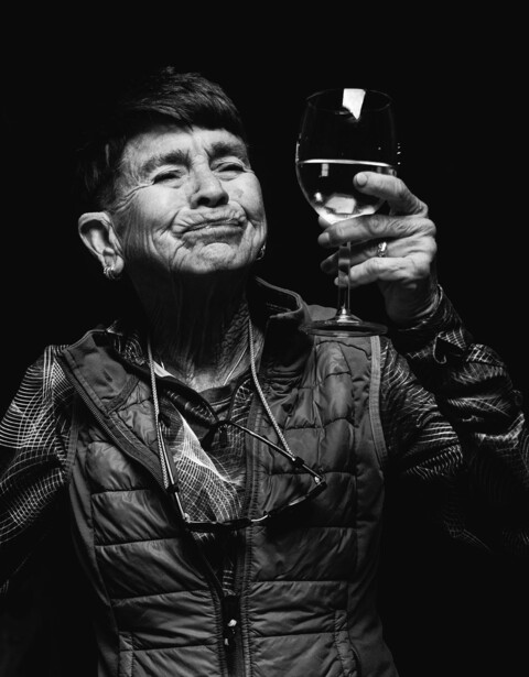 Man in quilted jacket holding up a small device against a dark background.
