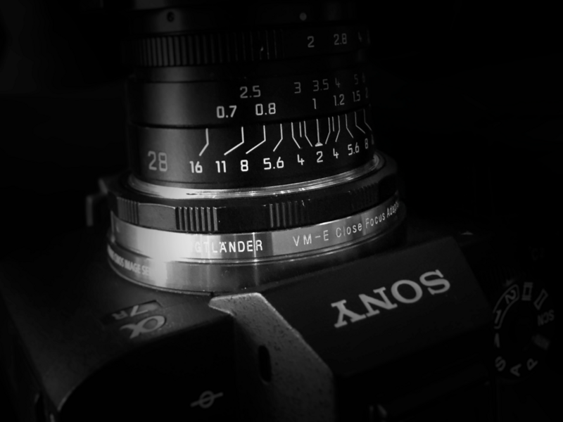 Close-up of a vintage camera lens showing distance markings, aperture values, and manual focus ring with depth of field scale.