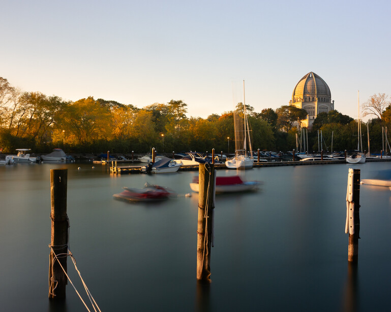 Long exposure photograph of a river and some boats in front of a Baha'i temple 