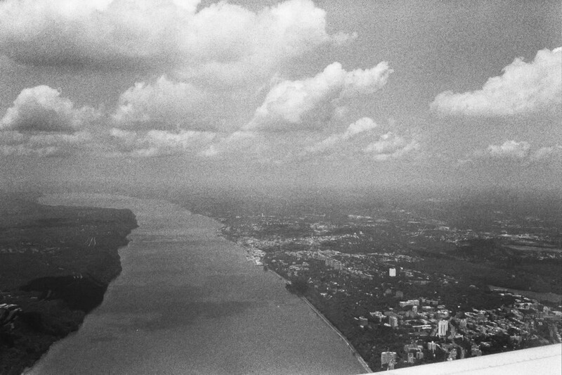 Aerial view of a river winding through developed landscape with cloudy sky.