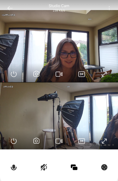 Screenshot of studio camera app showing two monitor feeds with a woman on camera and lighting equipment visible.