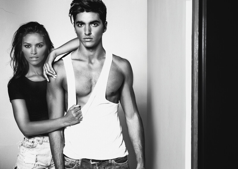 Black and white portrait of two people posing closely against a plain background.