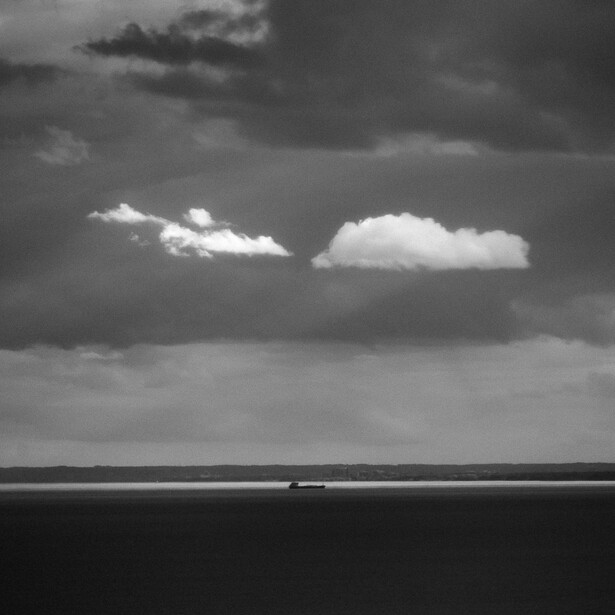 Black and white photo of a pair of sunlit clouds above Lake Ontario