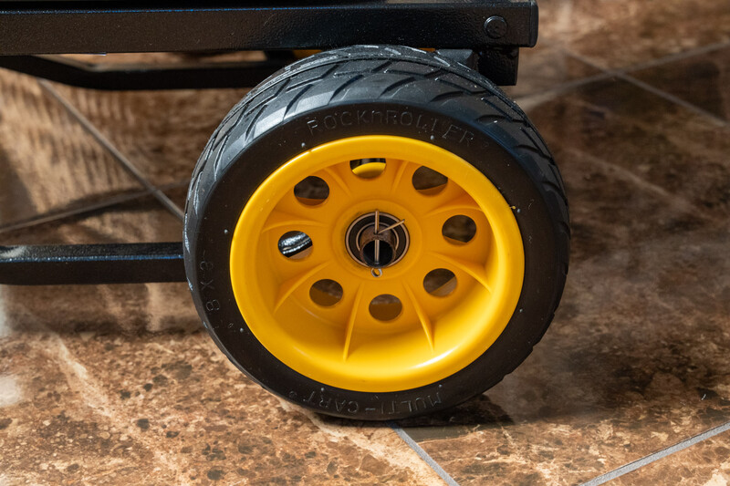 Yellow wheel with black tire mounted on a trailer axle, shot in natural daylight.