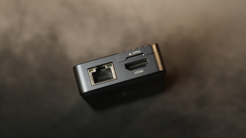 Compact travel adapter with Ethernet and HDMI ports on dark surface.