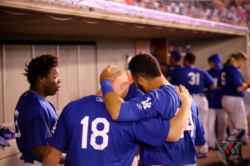Baseball players in blue uniforms huddle together in a dugout during a game.