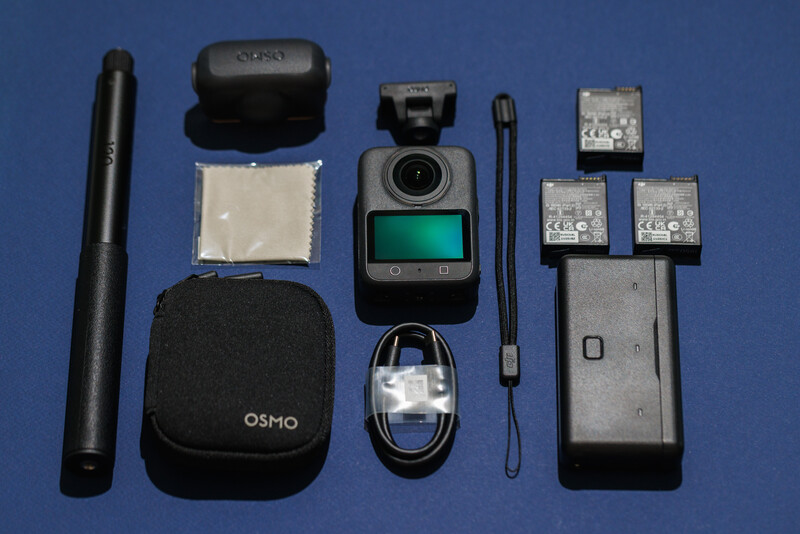 Flat lay of drone accessories and components arranged on blue background.