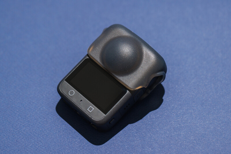 Compact camera with spherical ball mount attachment on blue background.