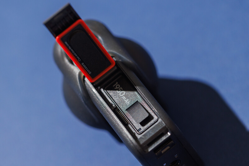 Close-up of a camera's film advance lever with red and black coloring against blue background.