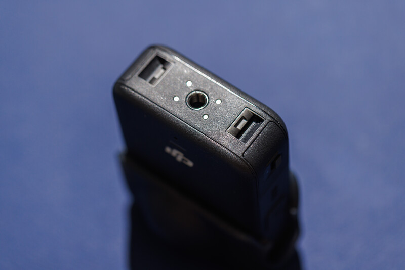 Black external hard drive or portable storage device against a blue surface.