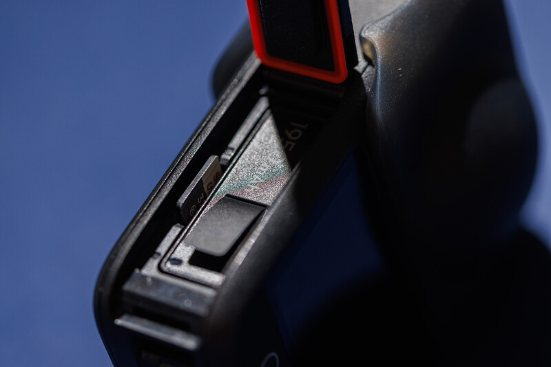 Close-up of a black camera flash unit with red accent panel against blue background.