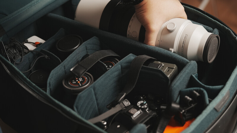 Photography gear organized in a camera bag with lenses, headphones, and accessories.