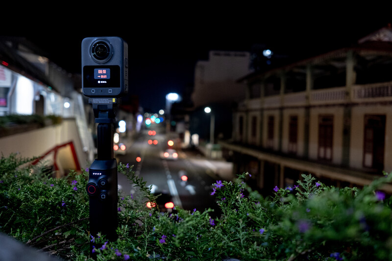 360-degree camera mounted on a pole overlooking a nighttime street with colonial architecture and vehicle headlights.
