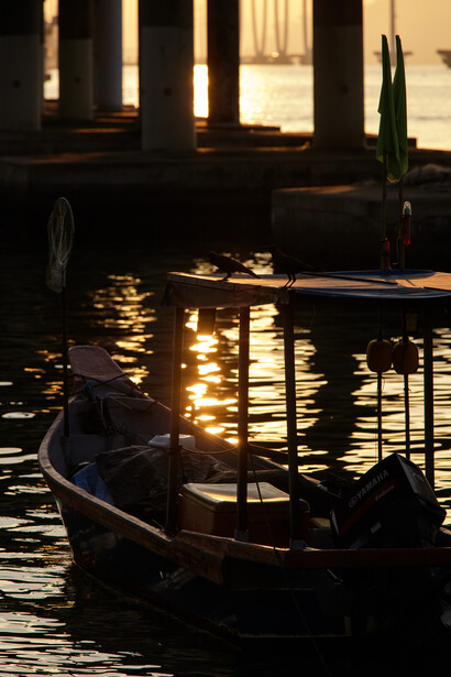 Gondola silhouetted against golden light reflecting on Venice canal water at dusk.
