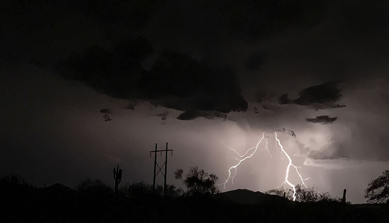 Lightning bolt striking the ground during a severe desert thunderstorm at night.