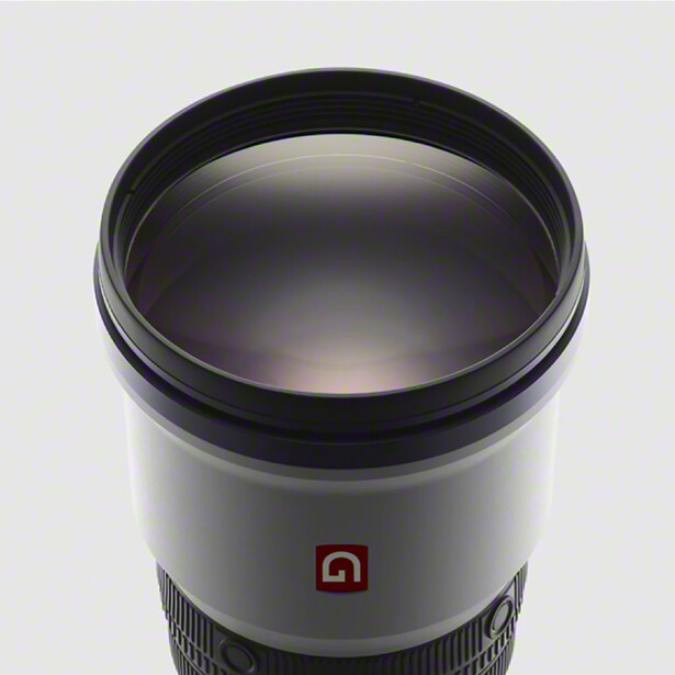 Top-down view of a telephoto lens with dome-shaped optical glass element and black barrel against white background.