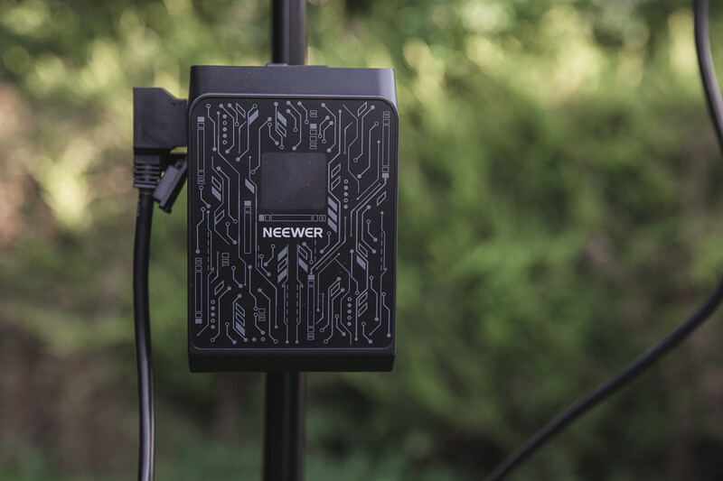 Neewer power bank with circuit board pattern mounted on a pole with cables attached.