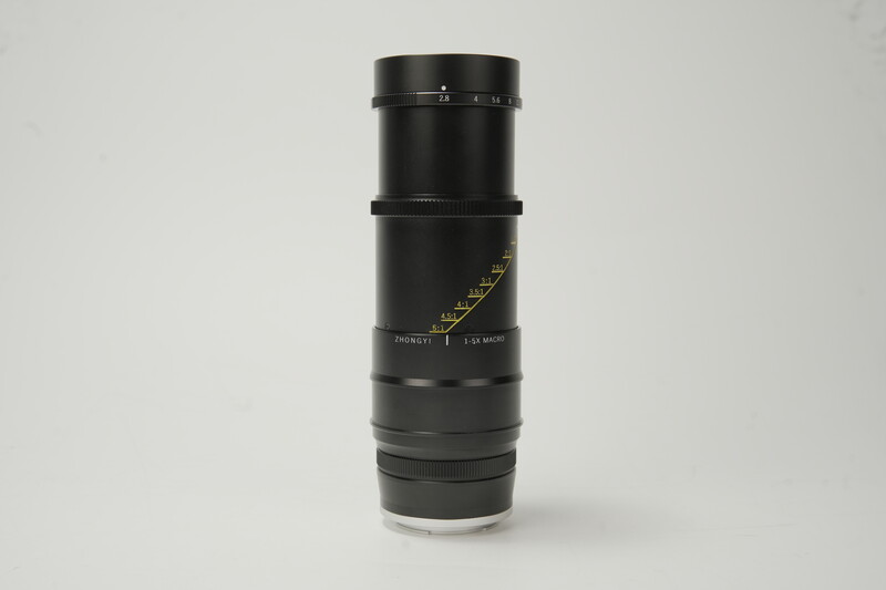 Black telephoto lens with focus ring and distance scale markings against neutral background.