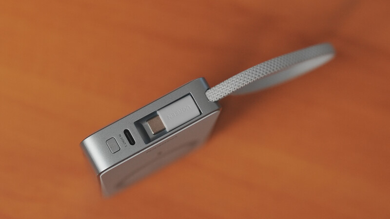 Digital thermometer with gray grip and display screen on warm orange background.