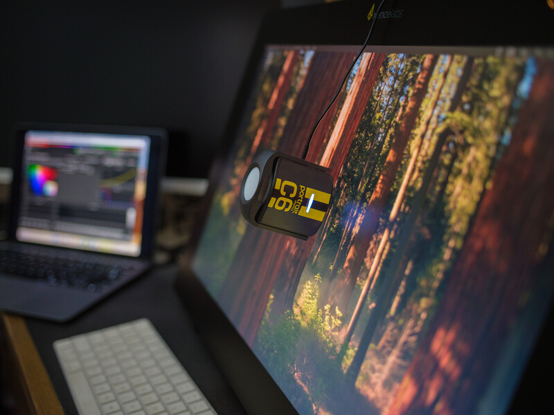Video editing workstation with a yellow taxi on a colorful street displayed on the main monitor.