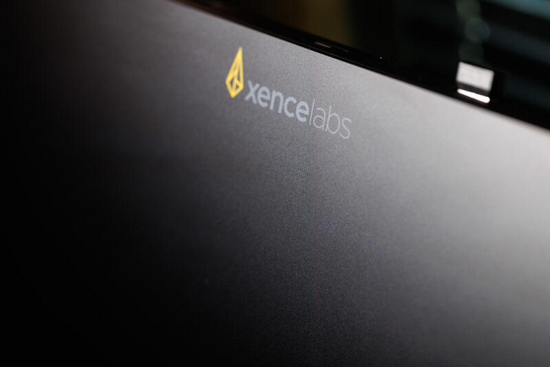 Close-up of a laptop lid with gold Xencelabs logo on dark surface.