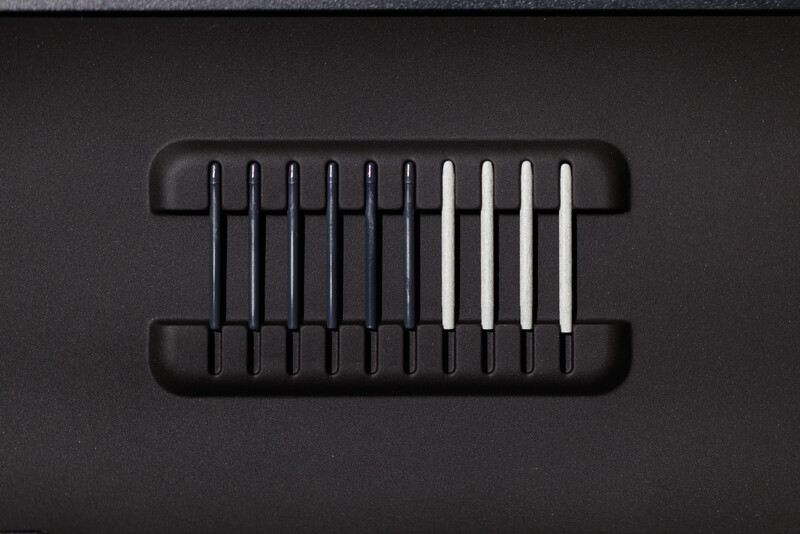 Black cable organizer with ten vertical slots holding mixed black and white cables against dark background.