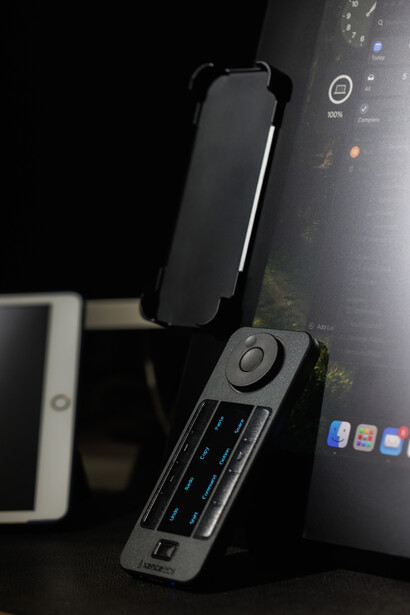 Smartphone mounted on a gimbal stabilizer next to a portable audio recorder on a dark desk.