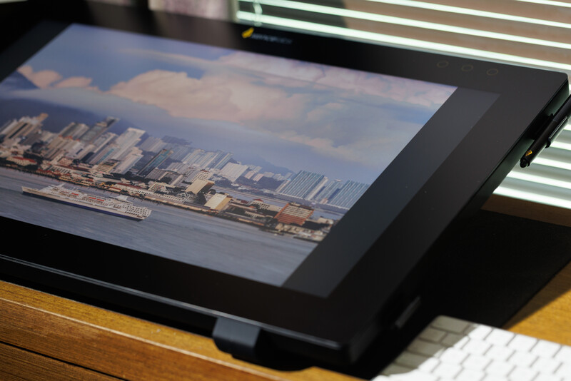 Digital tablet displaying cityscape photograph with waterfront and skyline, positioned at an angle on a wooden desk.