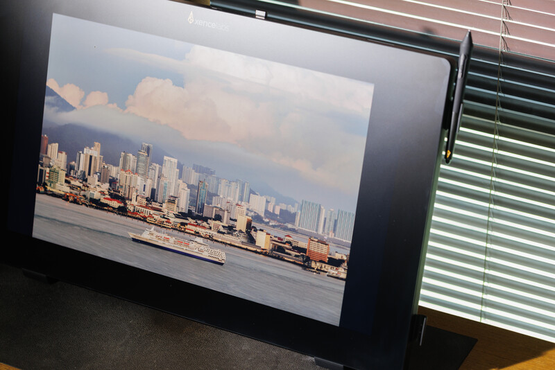 Cityscape photograph displayed on a monitor showing downtown skyline with waterfront and cloudy sky.