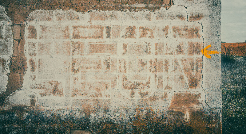 Aerial view of an abandoned agricultural field with faded rectangular plot divisions and weathered soil patterns.