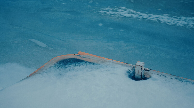Aerial view of a partially submerged structure with rust-colored framework in turquoise water.