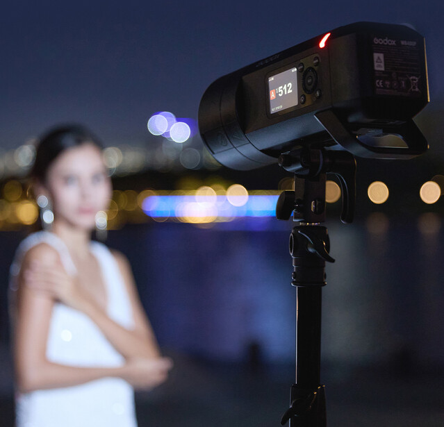 Professional video camera mounted on tripod with shallow depth of field, subject out of focus in background.