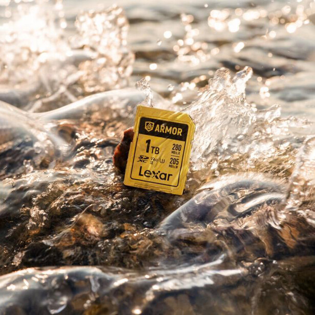 Yellow waterproof camera gear tag floating in turbulent water with splashes.