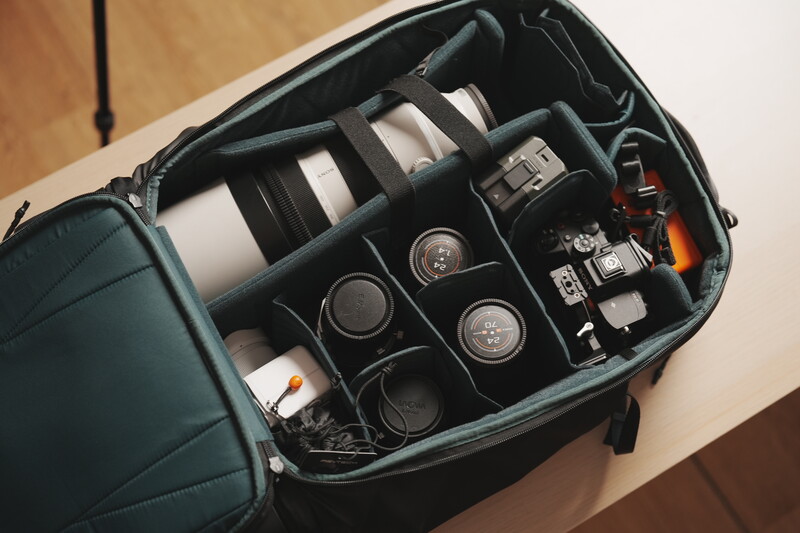 Open camera bag with organized compartments holding lenses, camera bodies, and accessories.