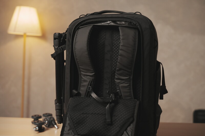 Black camera backpack displayed from behind on a desk, showing padded straps and ventilated back panel design.
