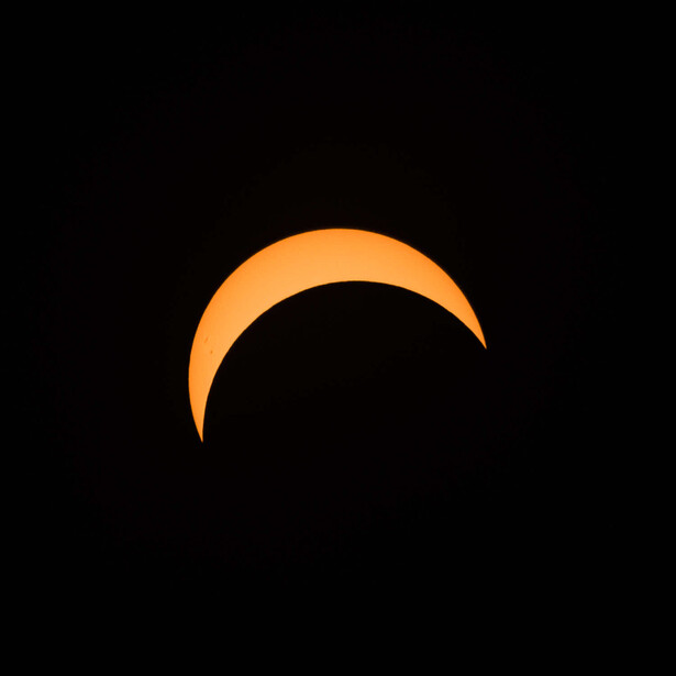 Orange crescent moon shape on black background.