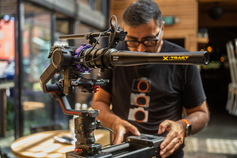 Photographer adjusting a cinema camera mounted on a tripod head in a studio setting.