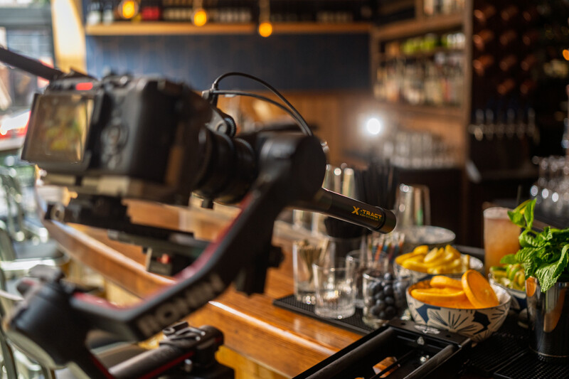 Professional microphone mounted on an arm rig in a podcast or recording studio setup with bar counter visible behind.