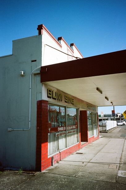 Storefront with red entry doors and pale green exterior wall under clear blue sky.