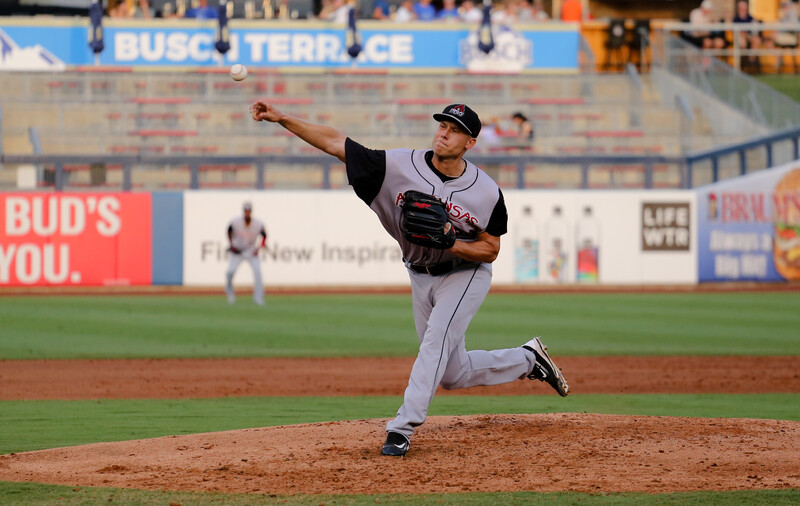 Pitcher mid-delivery throwing a baseball during a professional game at a stadium.
