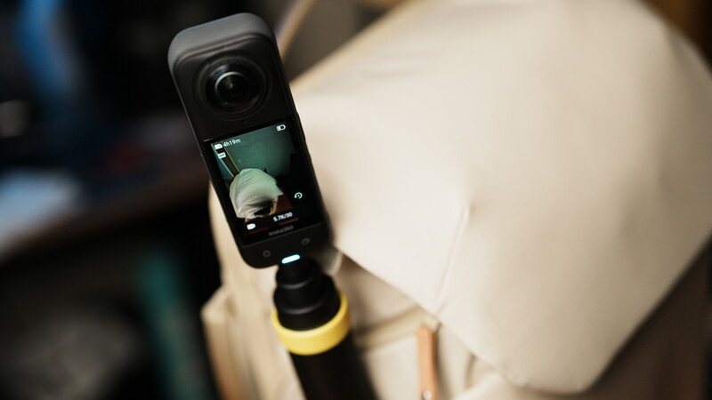 Action camera mounted on tripod displaying live preview of a spherical light modifier during setup.