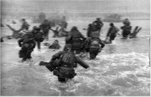 Soldiers wading through ocean surf during an amphibious military operation.