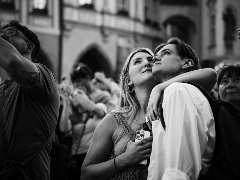Woman gazing upward with contemplative expression while standing among a crowd in an urban setting.