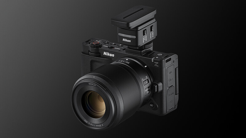 Nikon Z mirrorless camera with mounted lens, external flash, and battery grip against dark gray background.