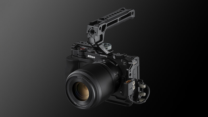 Nikon mirrorless camera with attached cinema rig and prime lens against dark background.